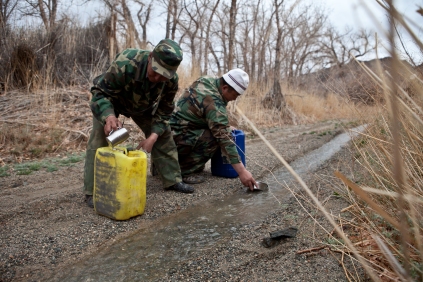Forest rangers collect drinking water from a small stream formed in the ruts of a passing ranger jeep. Scarcity of water is the biggest problem wildlife here faces with decreasing rainfall due to climate change.