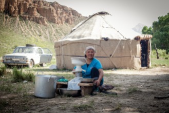A Kyrgyz herder churns fresh cream next to the summer yurt where they will stay till autumn.